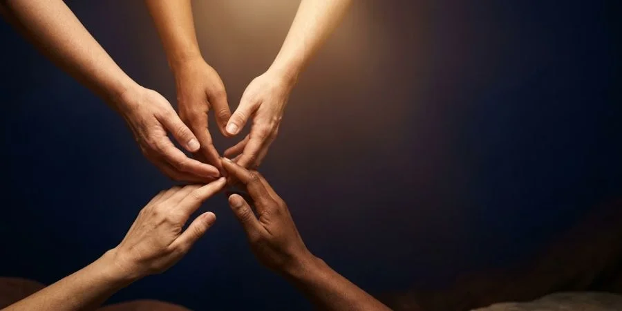 Diverse hands reaching toward each other in warm golden light, representing Bible verses about discrimination and unity
