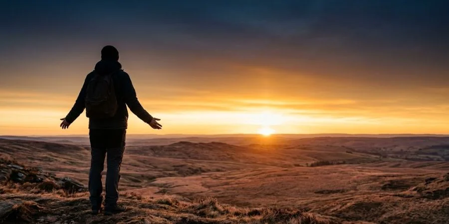A lone figure facing a golden dawn horizon, representing Bible verses about brokenness and God's promise of a hopeful future
