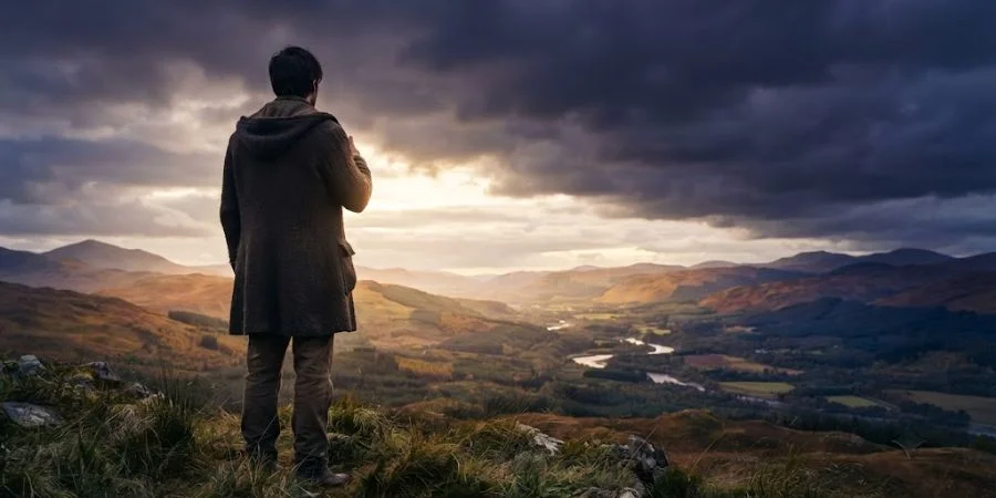 Solitary figure standing on a quiet hilltop, symbolizing comfort in Bible verses about the death of a father.