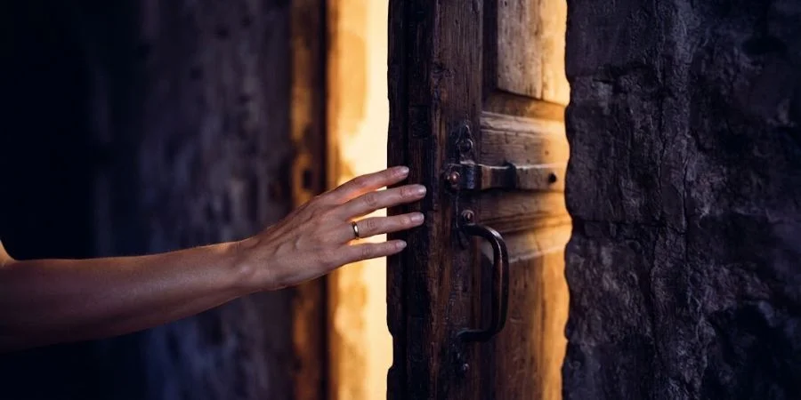 Hand reaching toward a light-filled doorway, symbolizing Bible verses for when you feel alone and reaching out