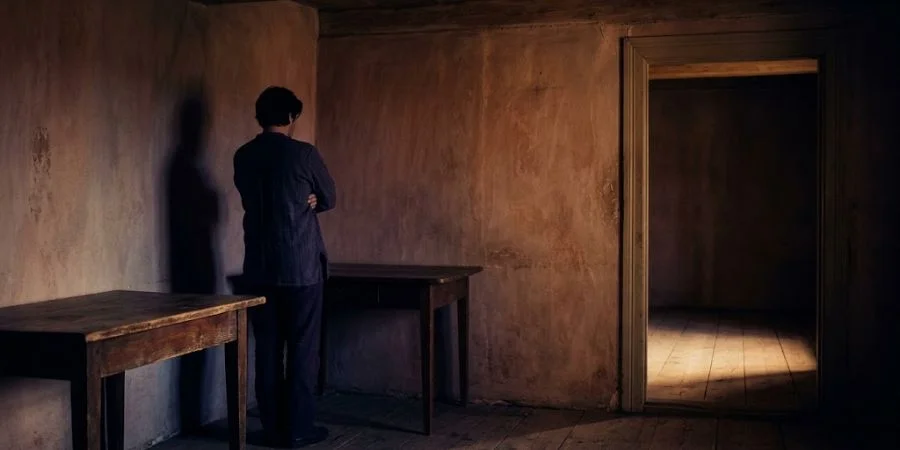A figure withdrawn alone in shadow, illustrating Bible verses about arguing and the isolation behind conflict