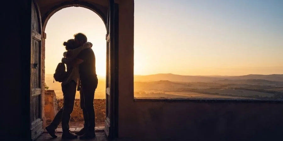 Two silhouettes embracing in golden light, symbolizing the promise found in Bible verses about distance relationships.