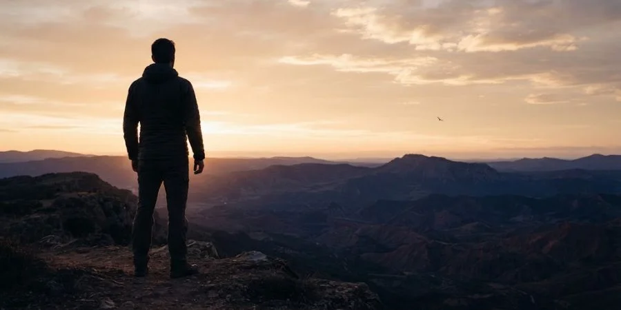 Person standing at dawn facing the horizon, symbolizing Bible verses about distance relationships and enduring strength.