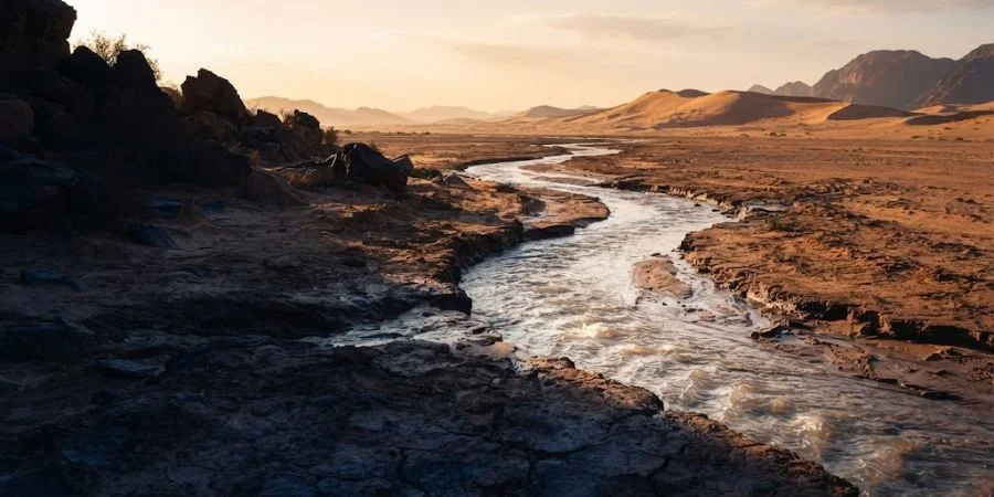 A river cutting through desert sand at dawn, symbolizing Bible verses about second chances and God's new beginnings.